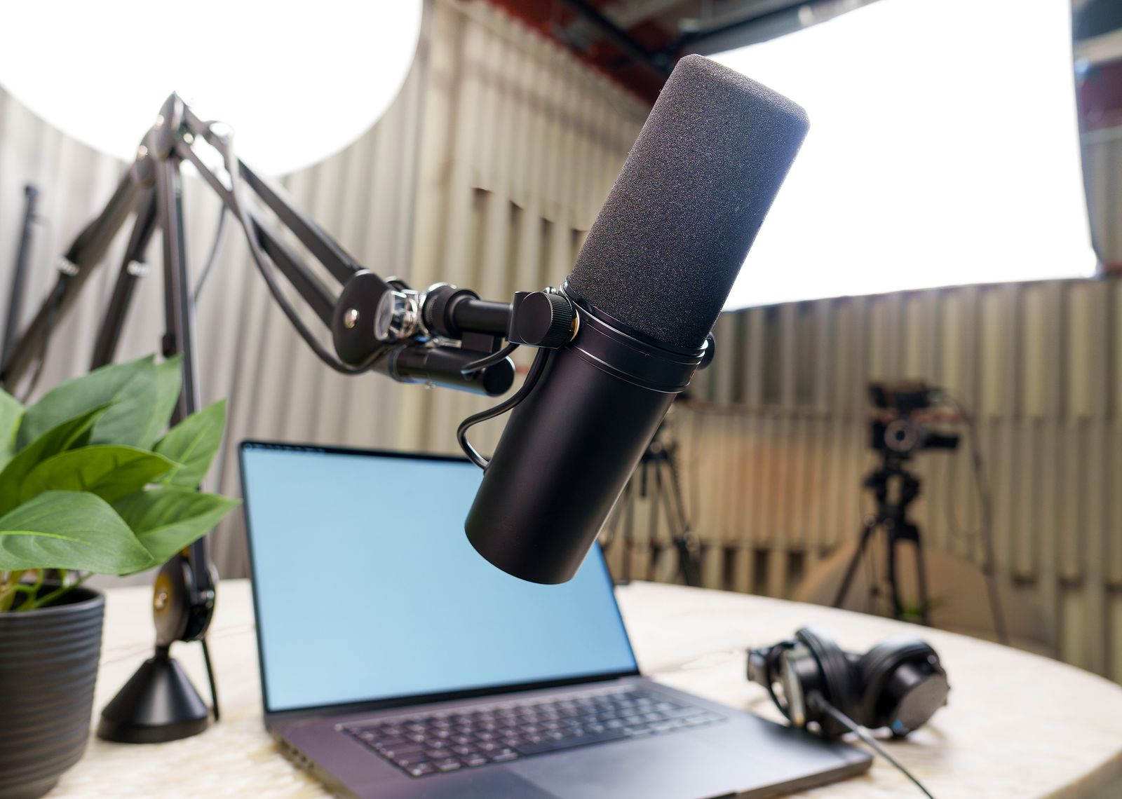 A microphone on an arm, a laptop and headphones set up for recording