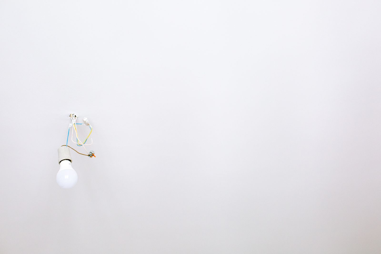 A bare bulb hanging on its wire from a white ceiling