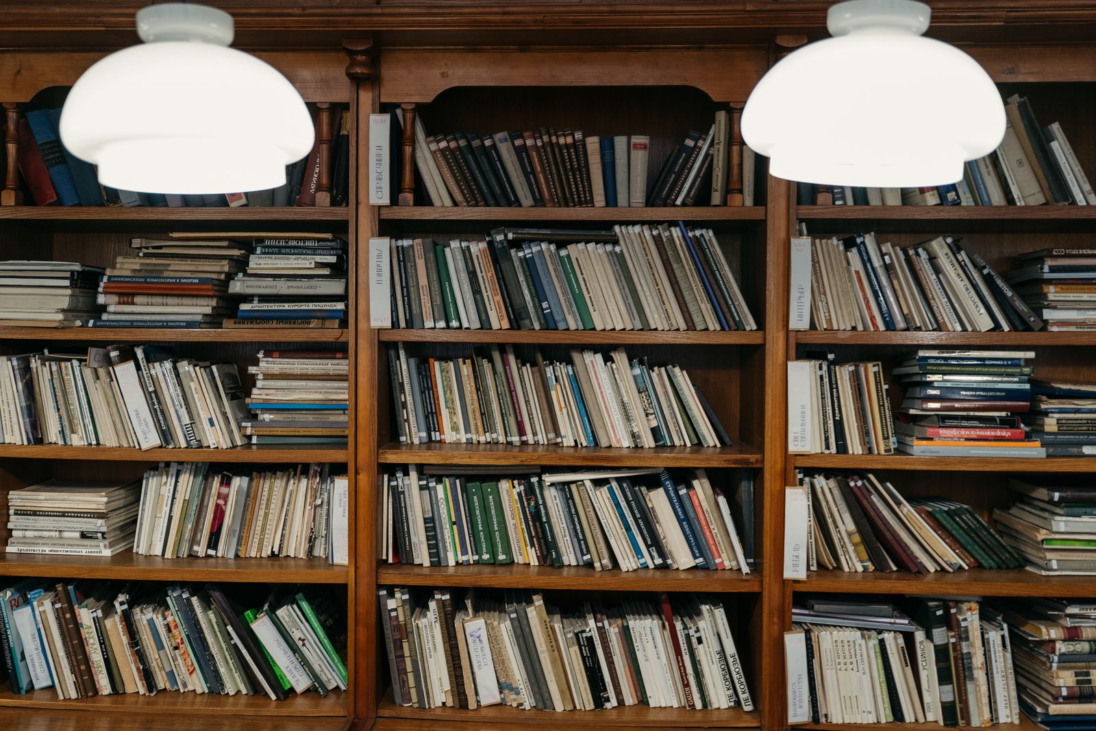 Tall wooden library shelves under two white pendant lamps