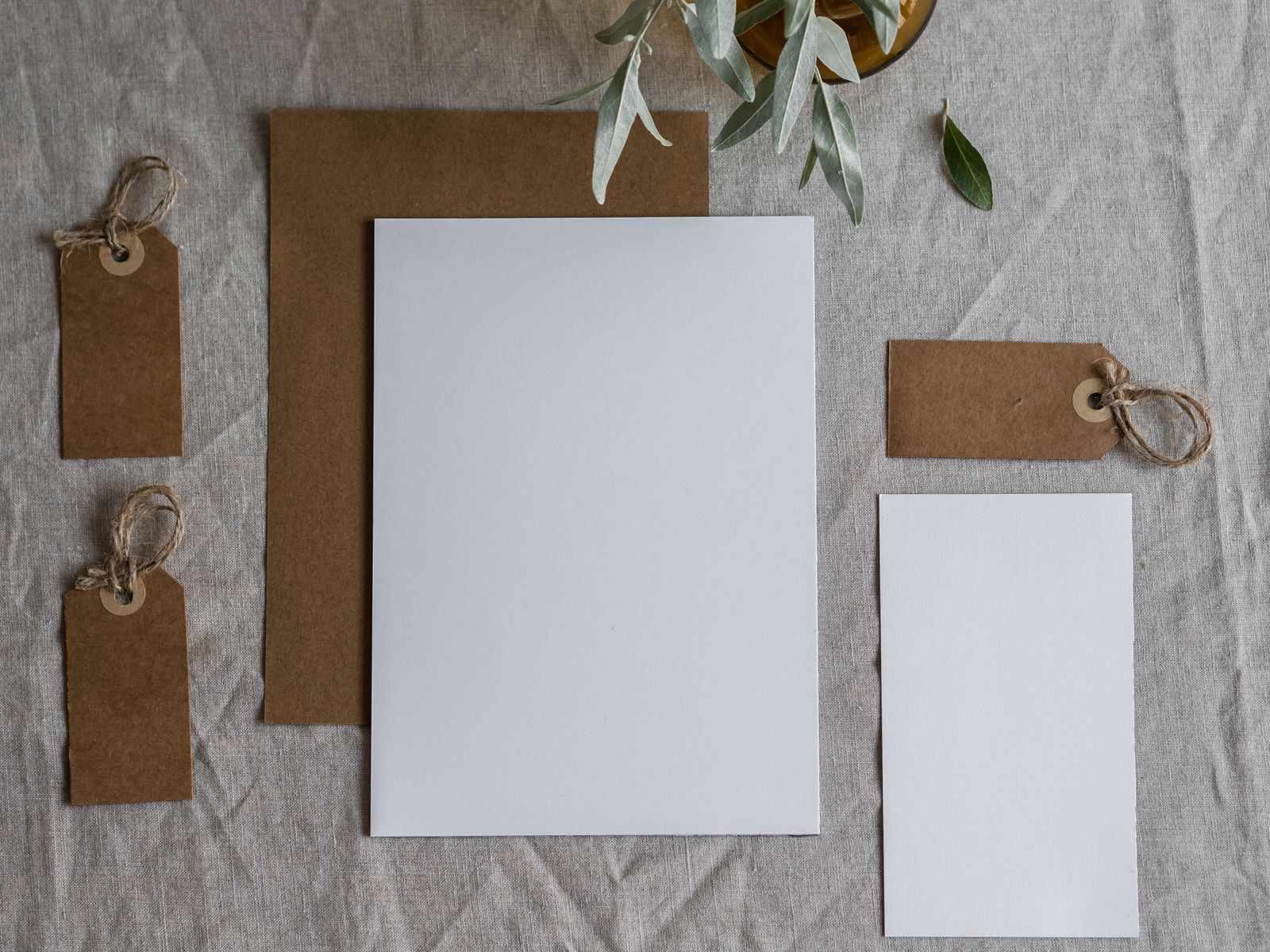 Blank letterhead, card and kraft tags laid out on linen