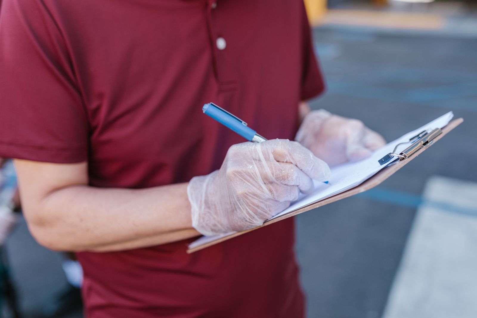 A gloved hand writing on a field sheet clipped to a board