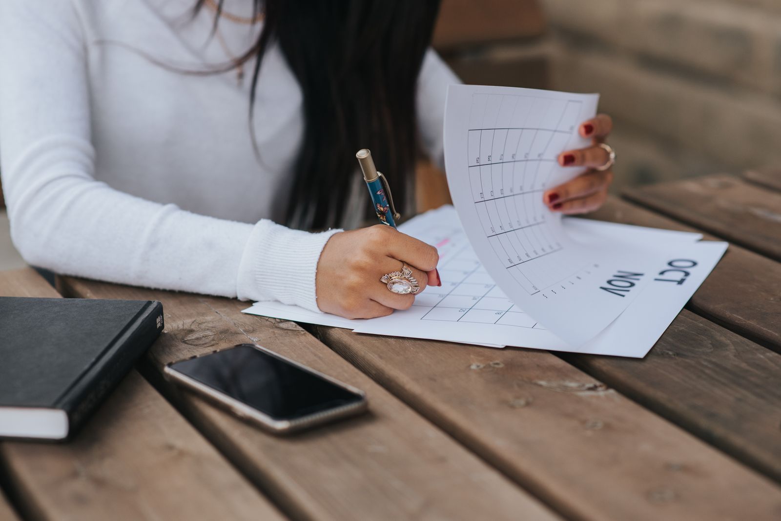 A person writing a monthly plan on paper at a wooden table