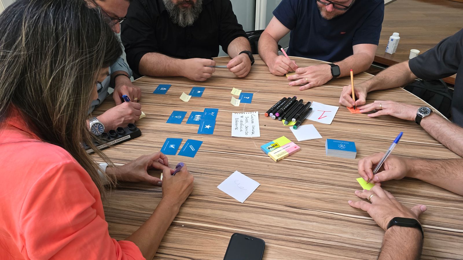 People around a table with cards, markers and sticky notes in a workshop