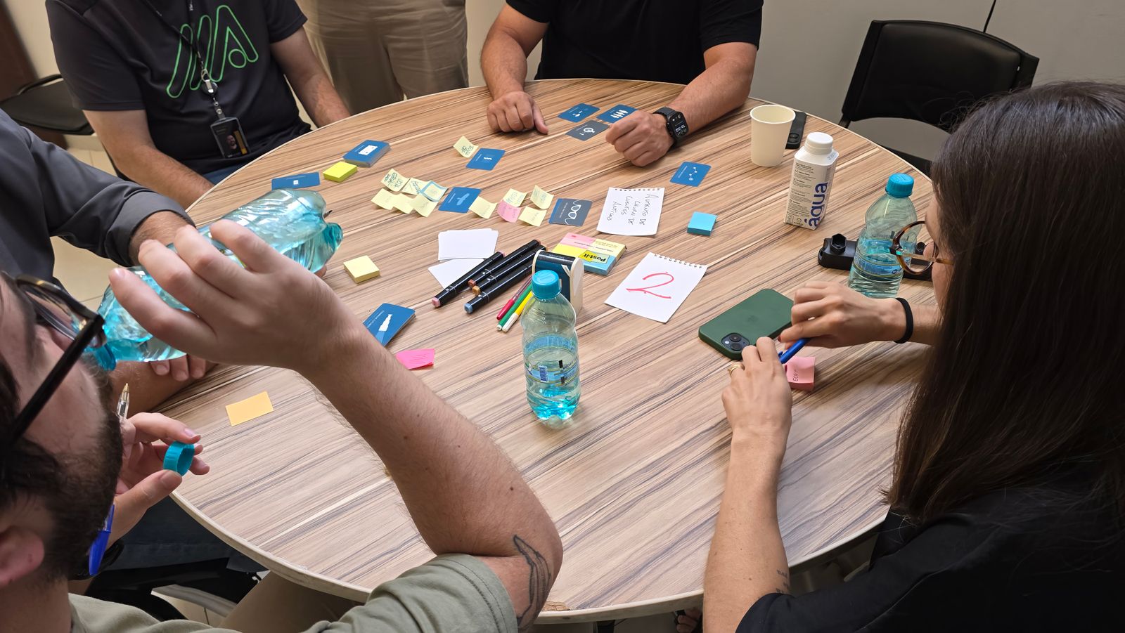 Hands moving cards and sticky notes on a round table during a workshop