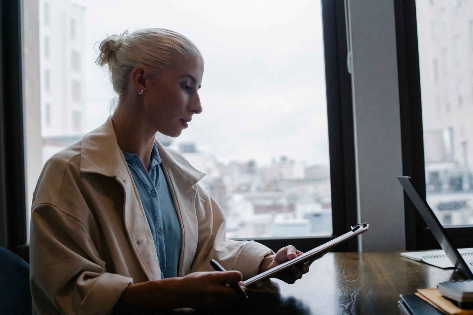 A woman checking figures on a tablet at a desk by the office window