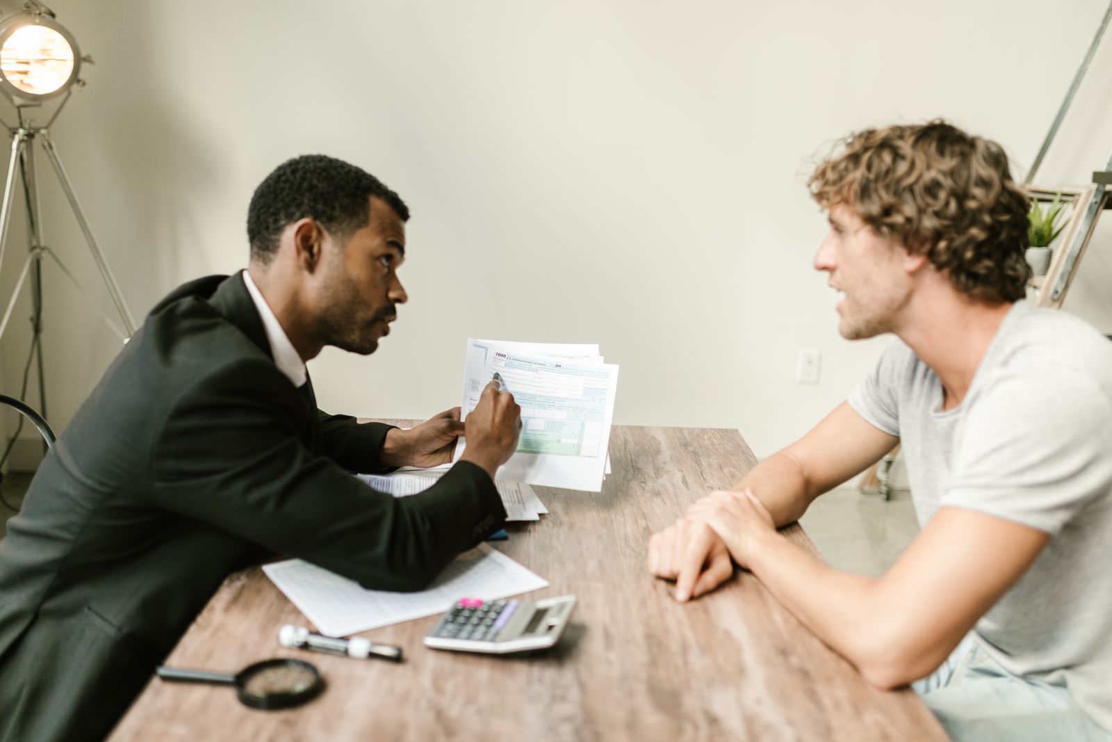 An adviser going through papers with a client across a desk with a calculator