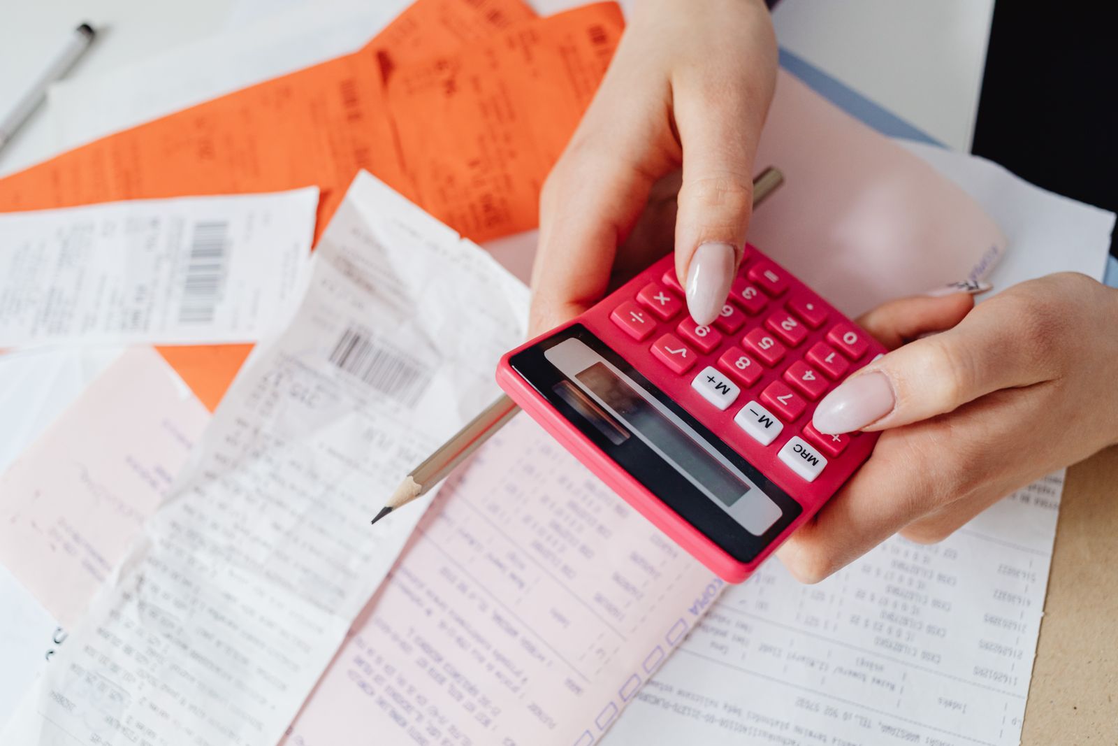 Receipts and bills on a desk beside a calculator