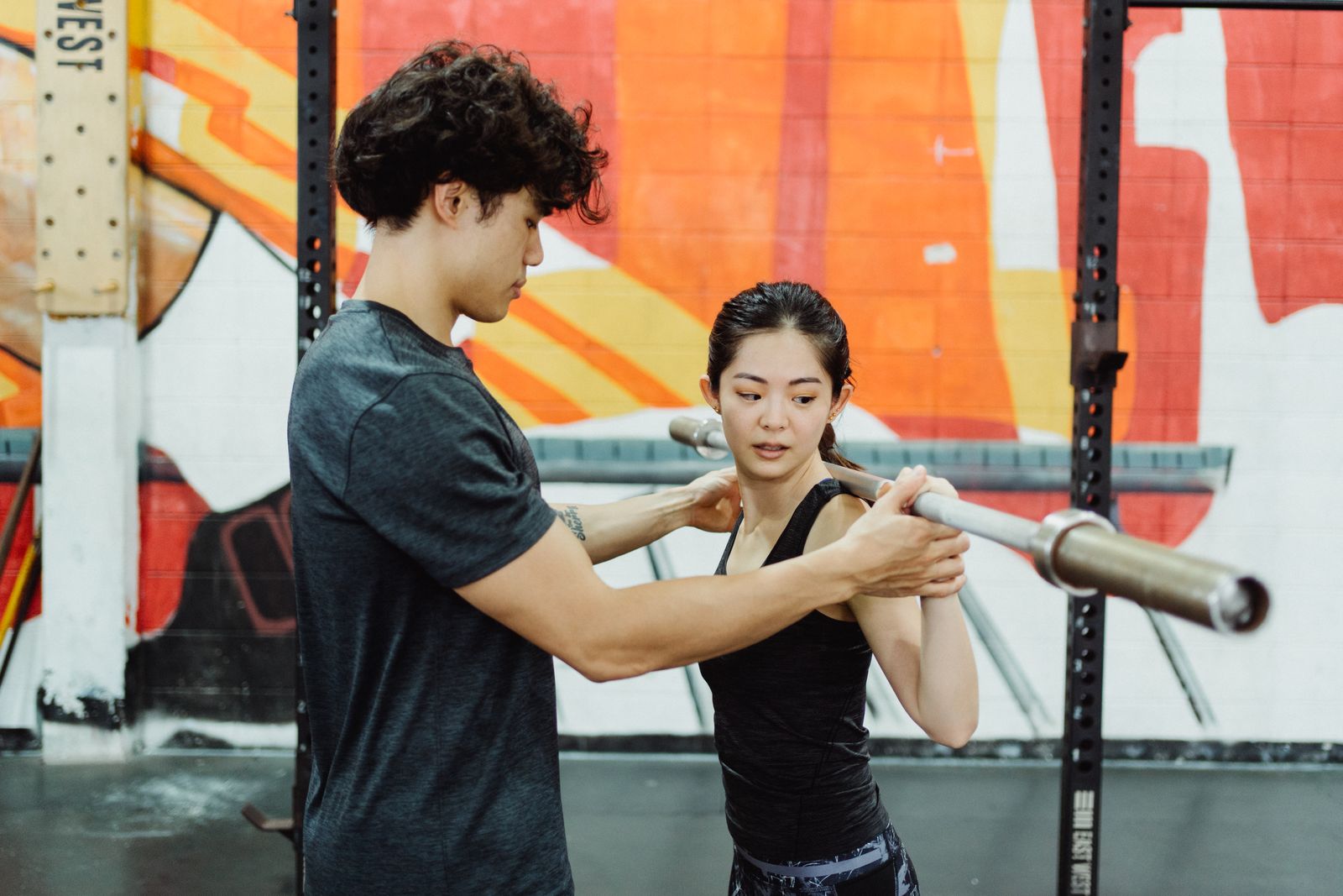 A personal trainer guides a woman's grip on the barbell