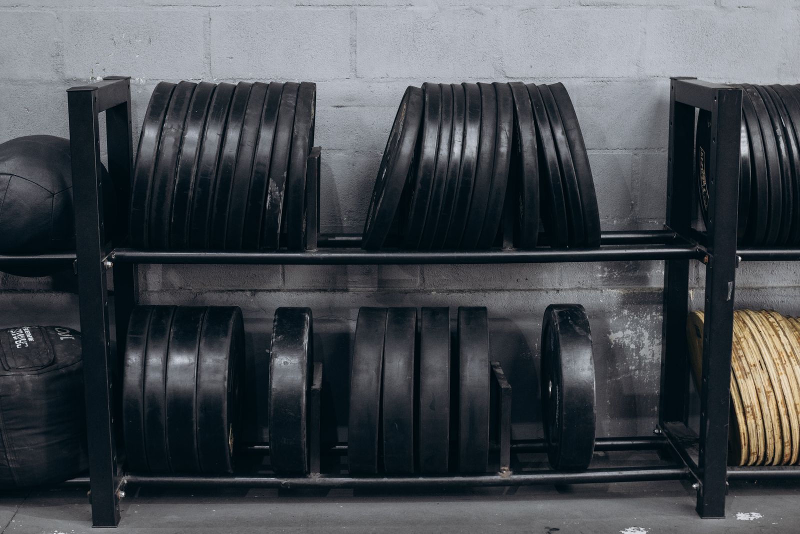 Rows of black bumper plates stored on a rack