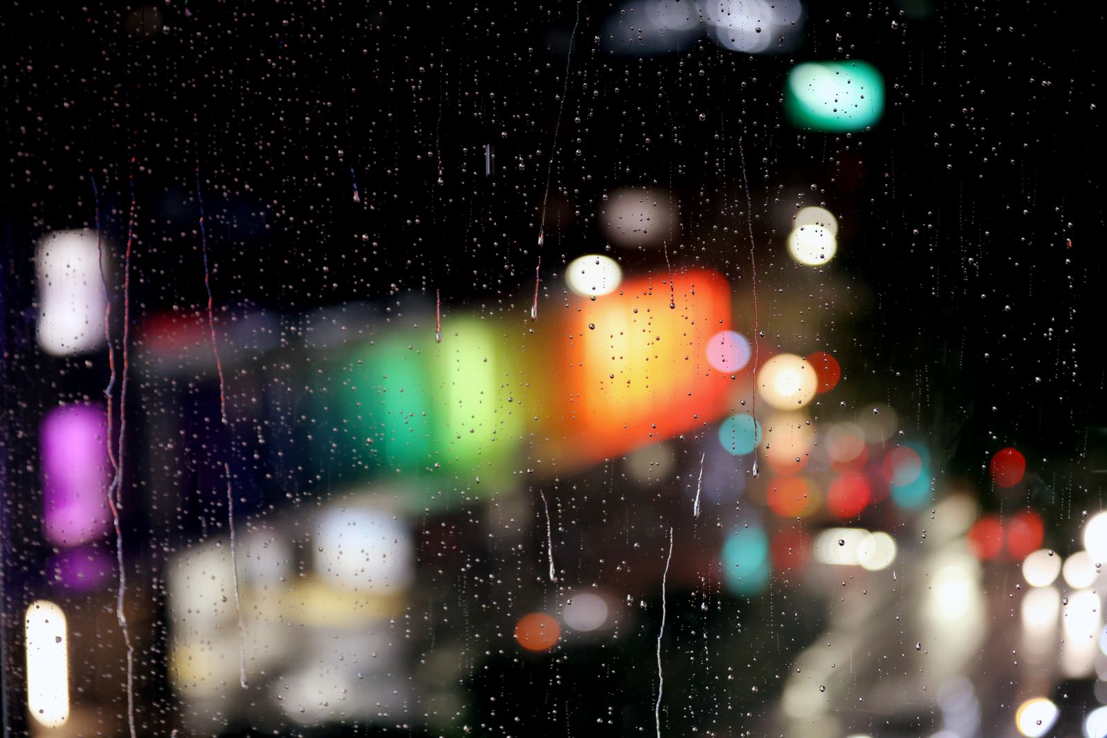 City lights at night seen through a window covered in raindrops