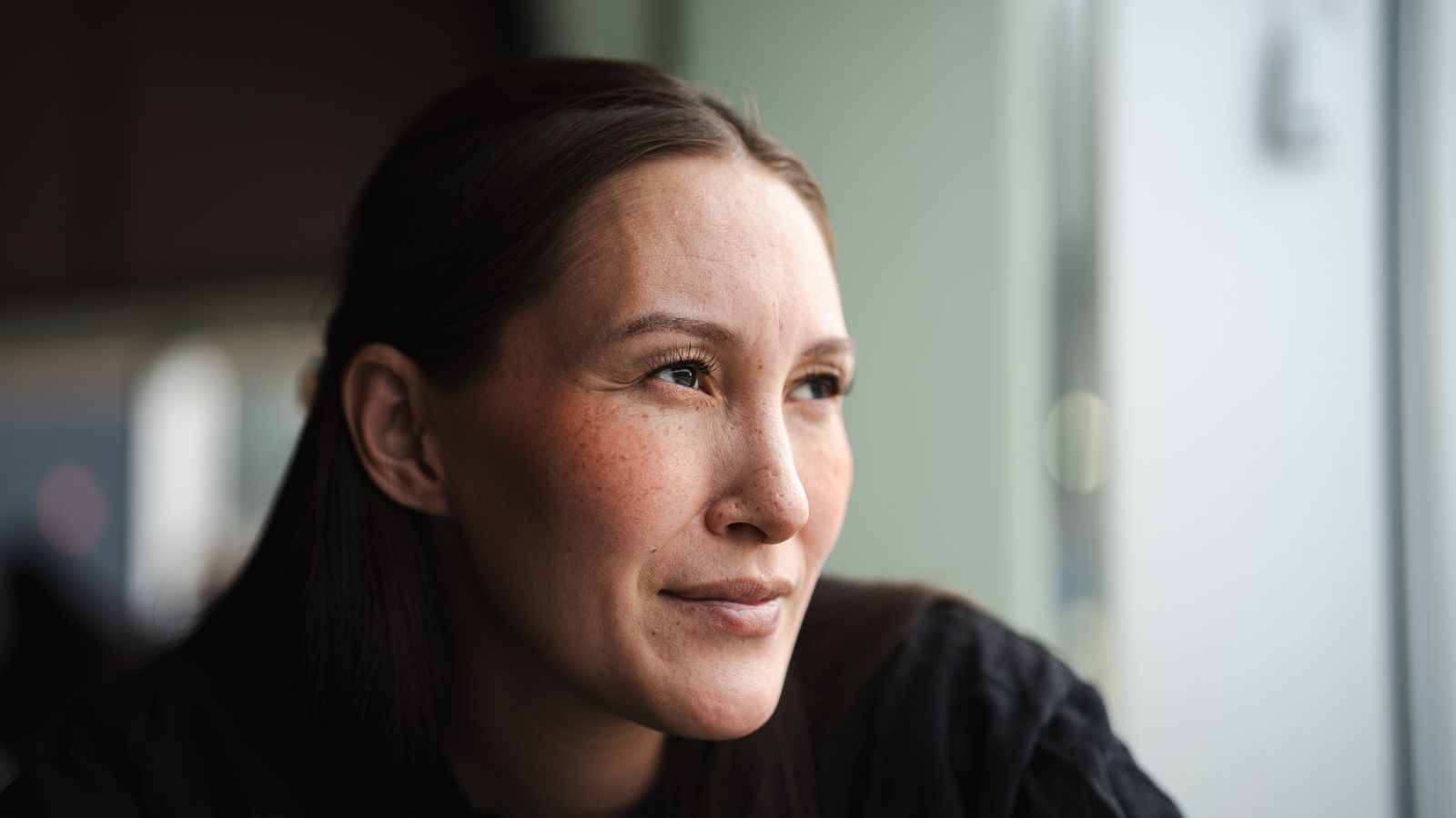 A woman looking out of a window in soft side light