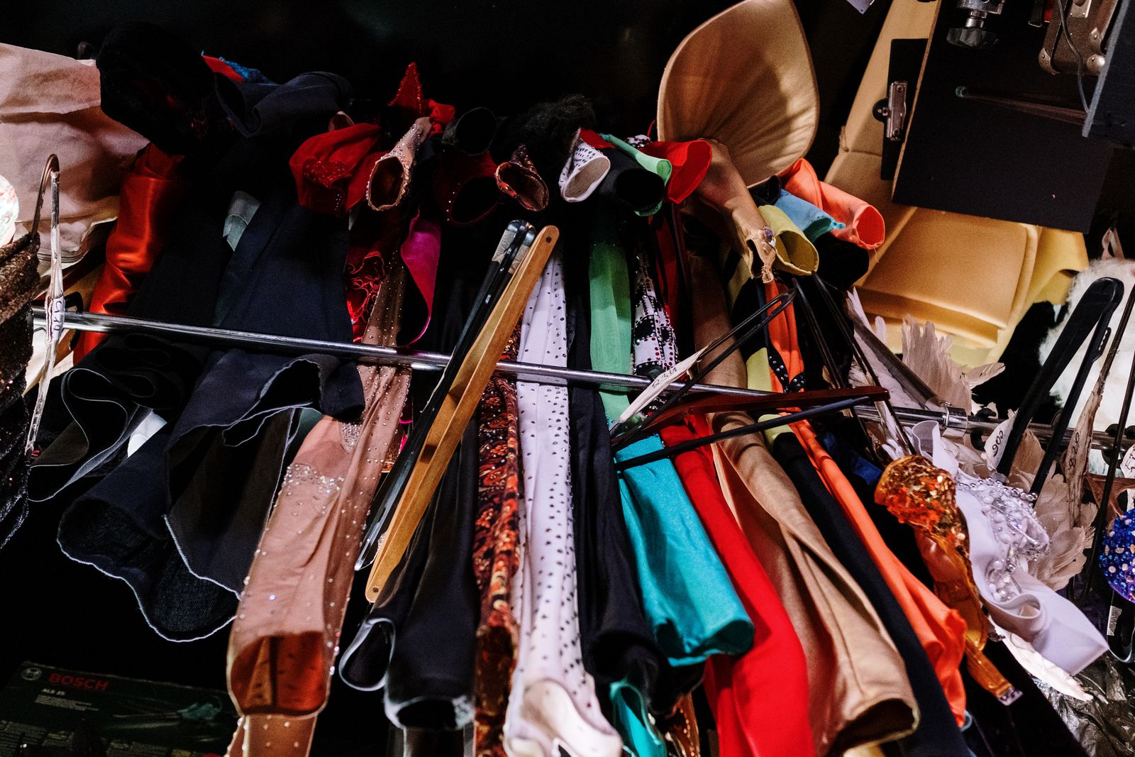 A packed rail of colourful costumes on hangers, sequins, velvet and capes