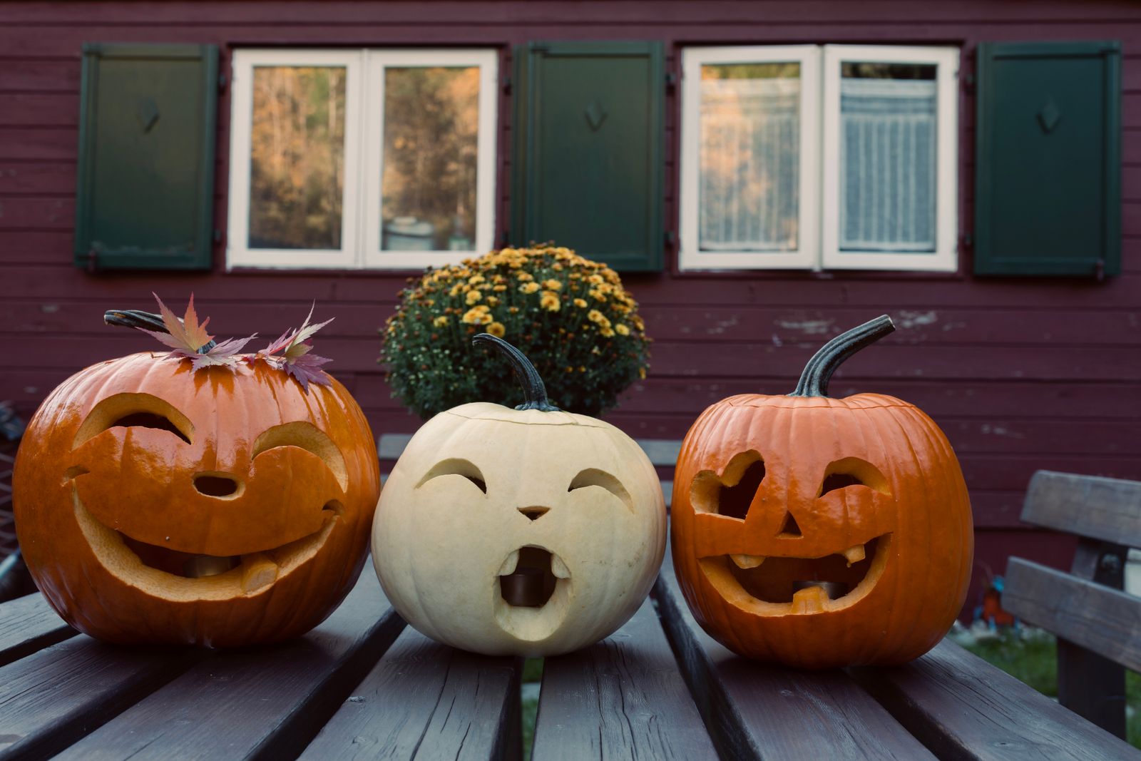 Three carved pumpkins with funny faces on a wooden table outdoors