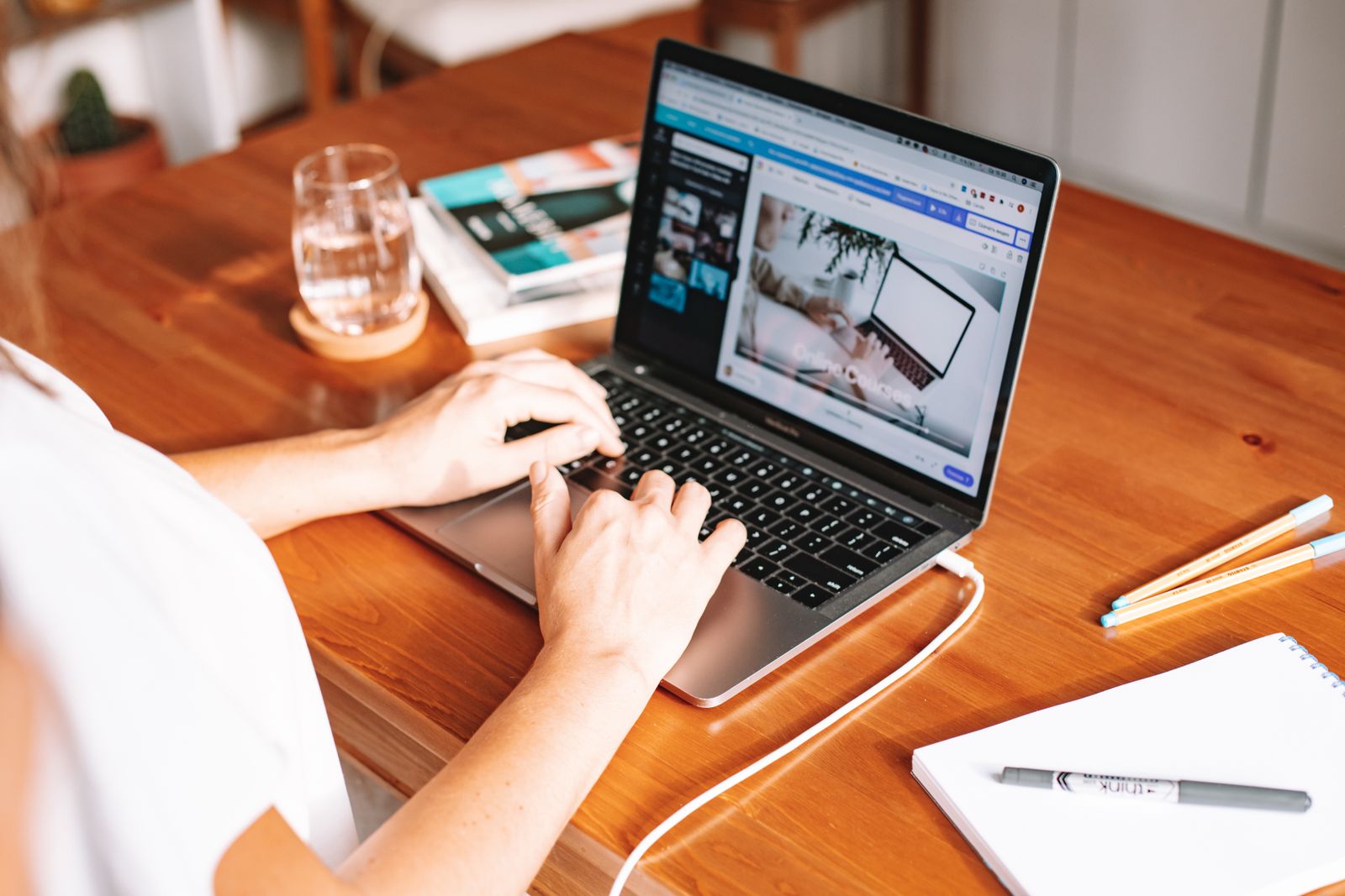 Hands typing on a laptop on a wooden table