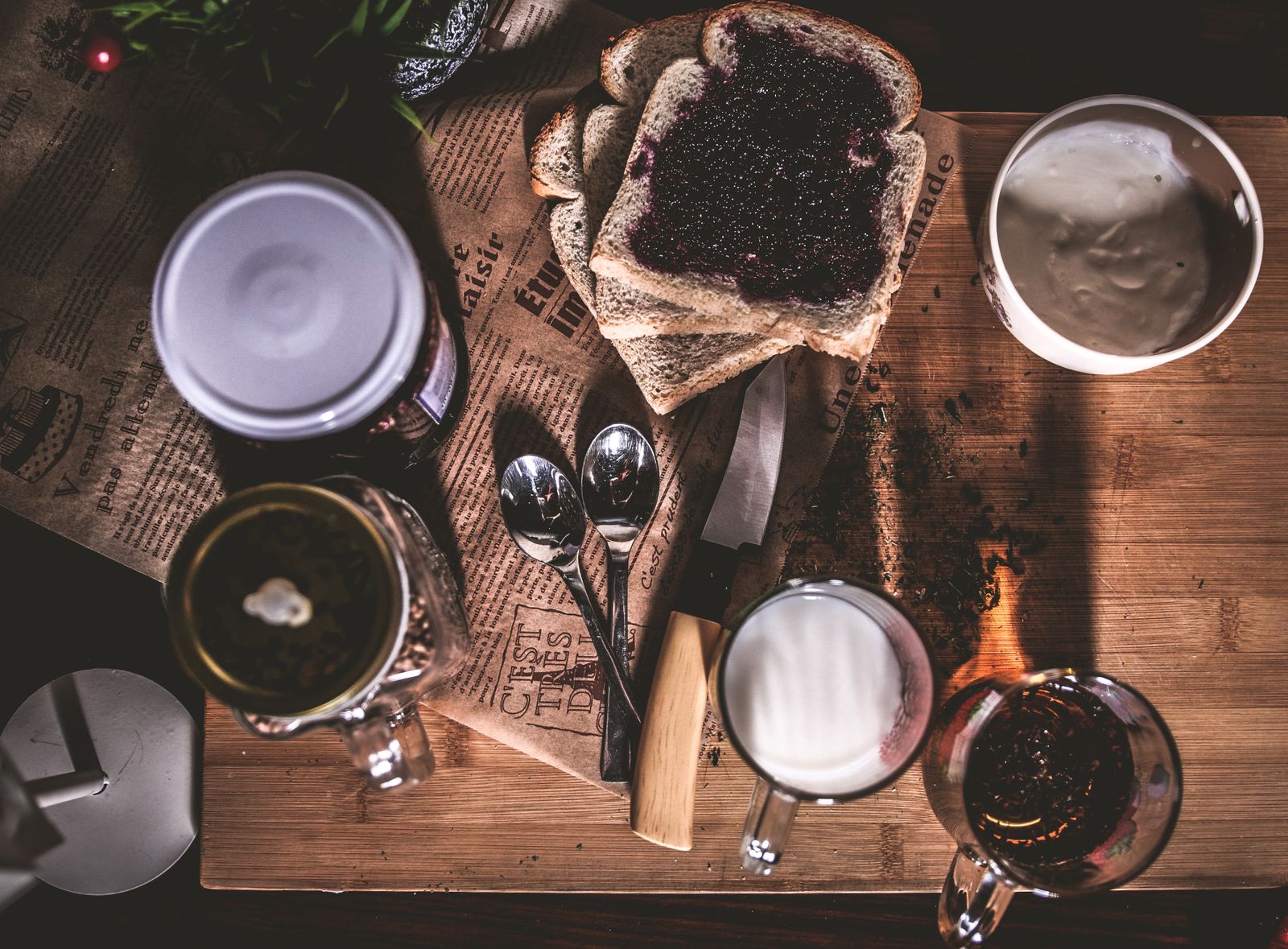 Bread, jam, cream and coffee on a wooden breakfast table