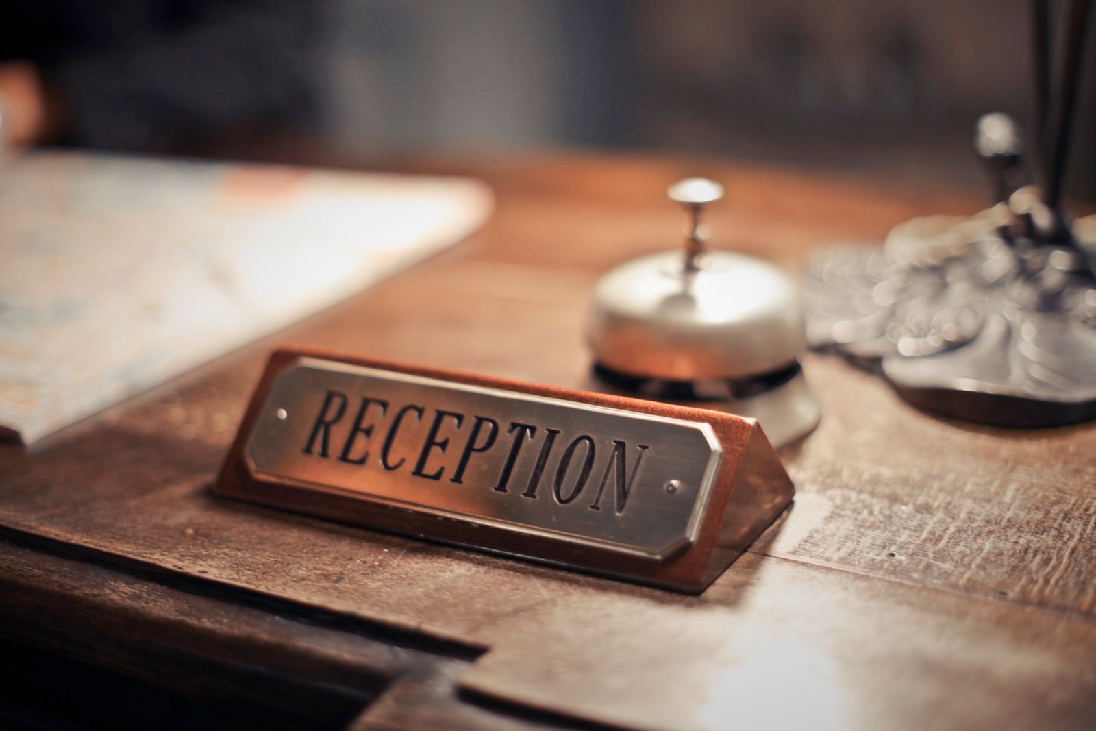 A brass reception sign and a service bell on a wooden front desk