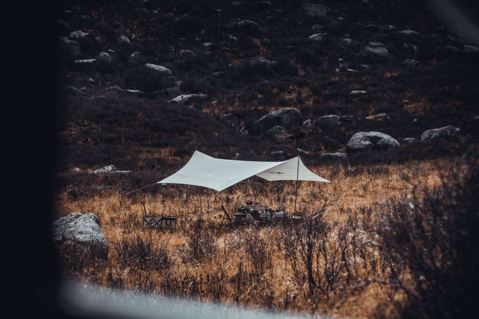 A camp shelter in a dry high valley with mountains behind
