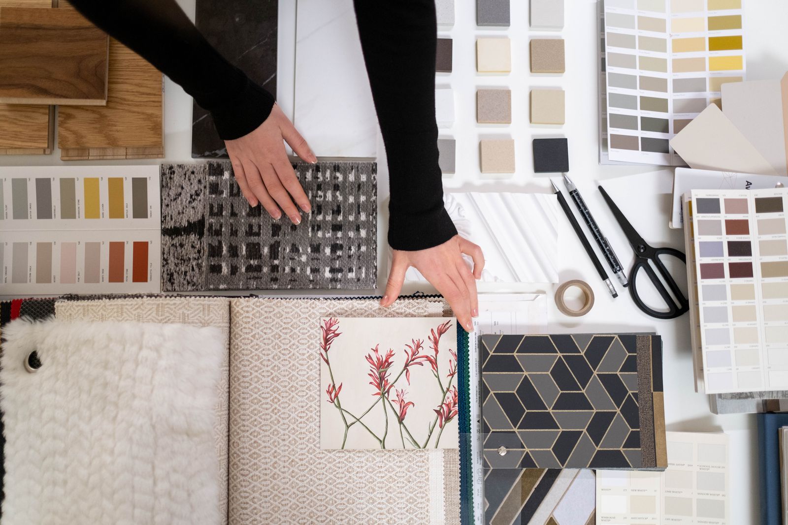 A designer arranging tile, fabric and colour samples on a studio table