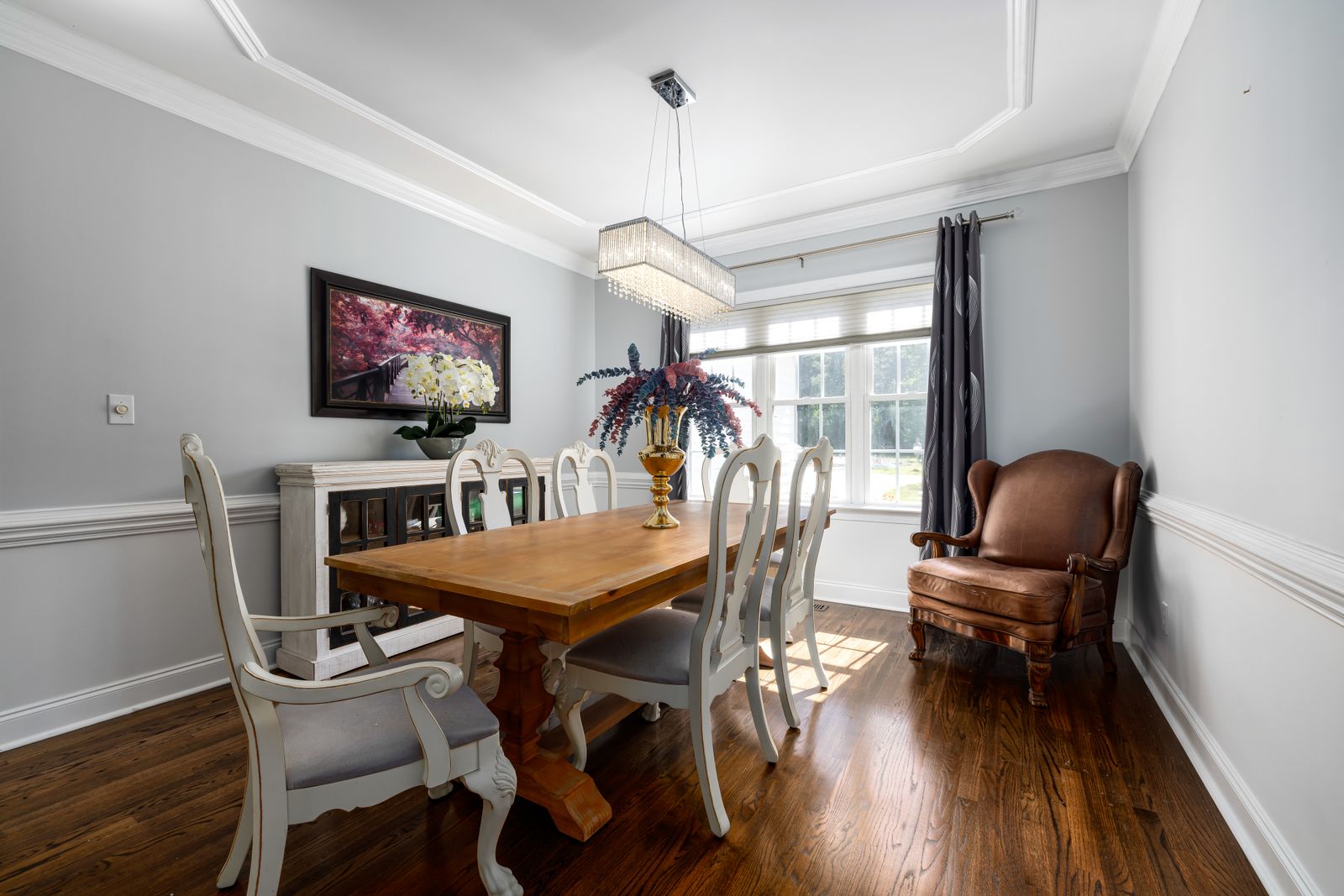 A bright dining room with a wooden table, vintage chairs and a chandelier