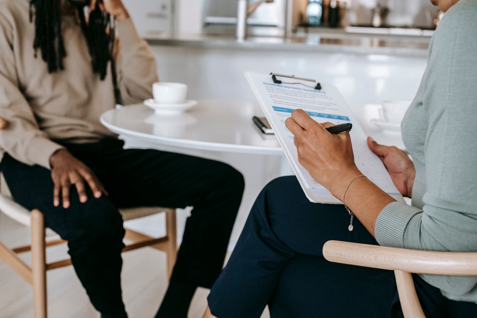 An interviewer with a clipboard taking notes while a job seeker answers