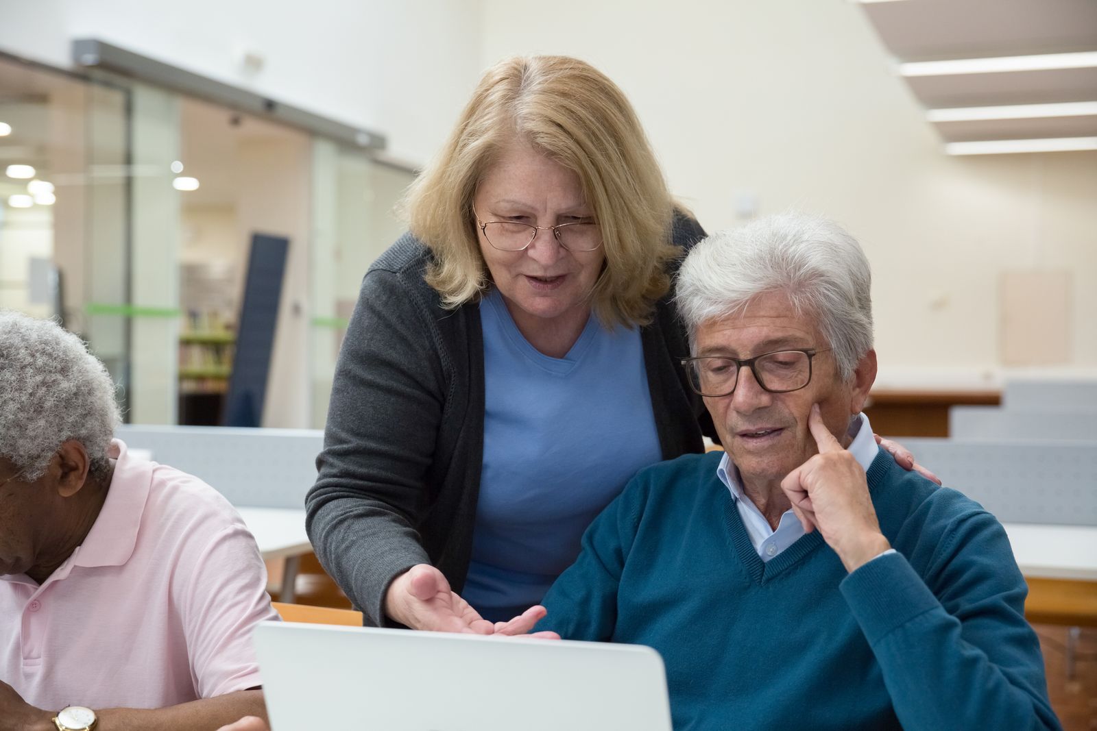 A volunteer showing an older man something on a laptop screen