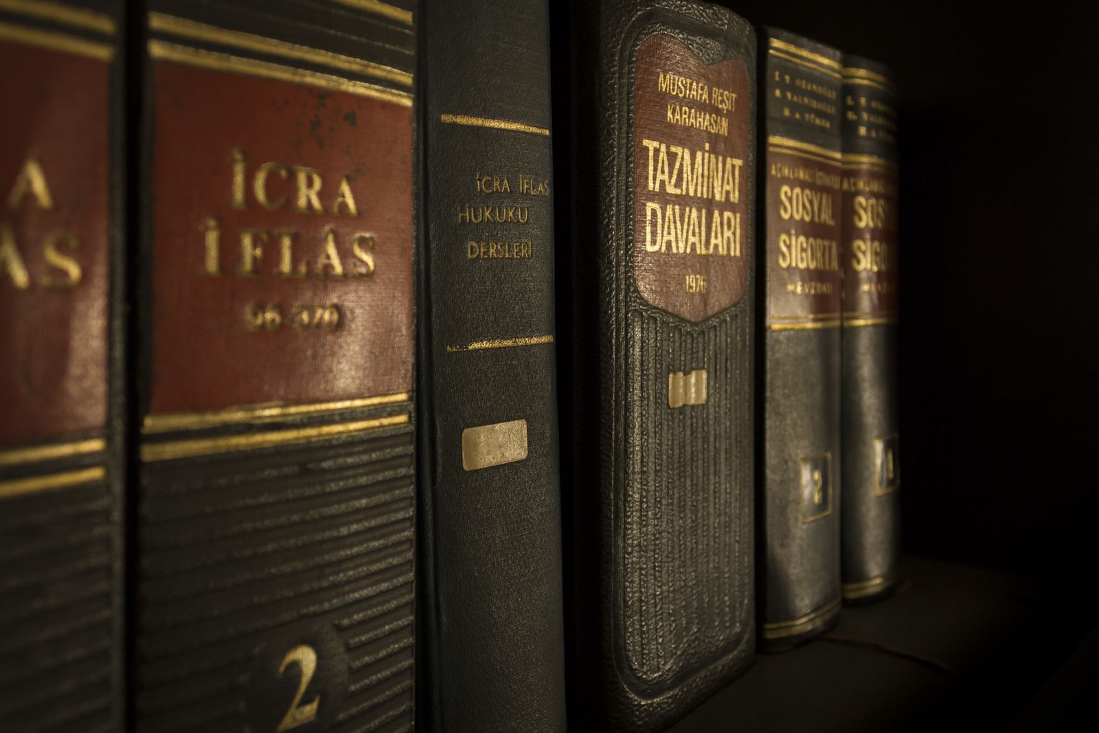 Law books with worn leather spines on a dark shelf