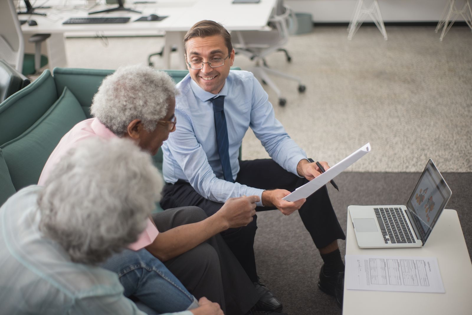 An adviser going through papers with an older couple on a sofa