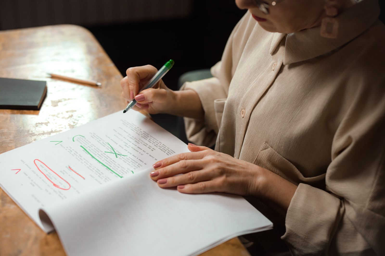 An editor marking corrections on a printed manuscript with a green pen