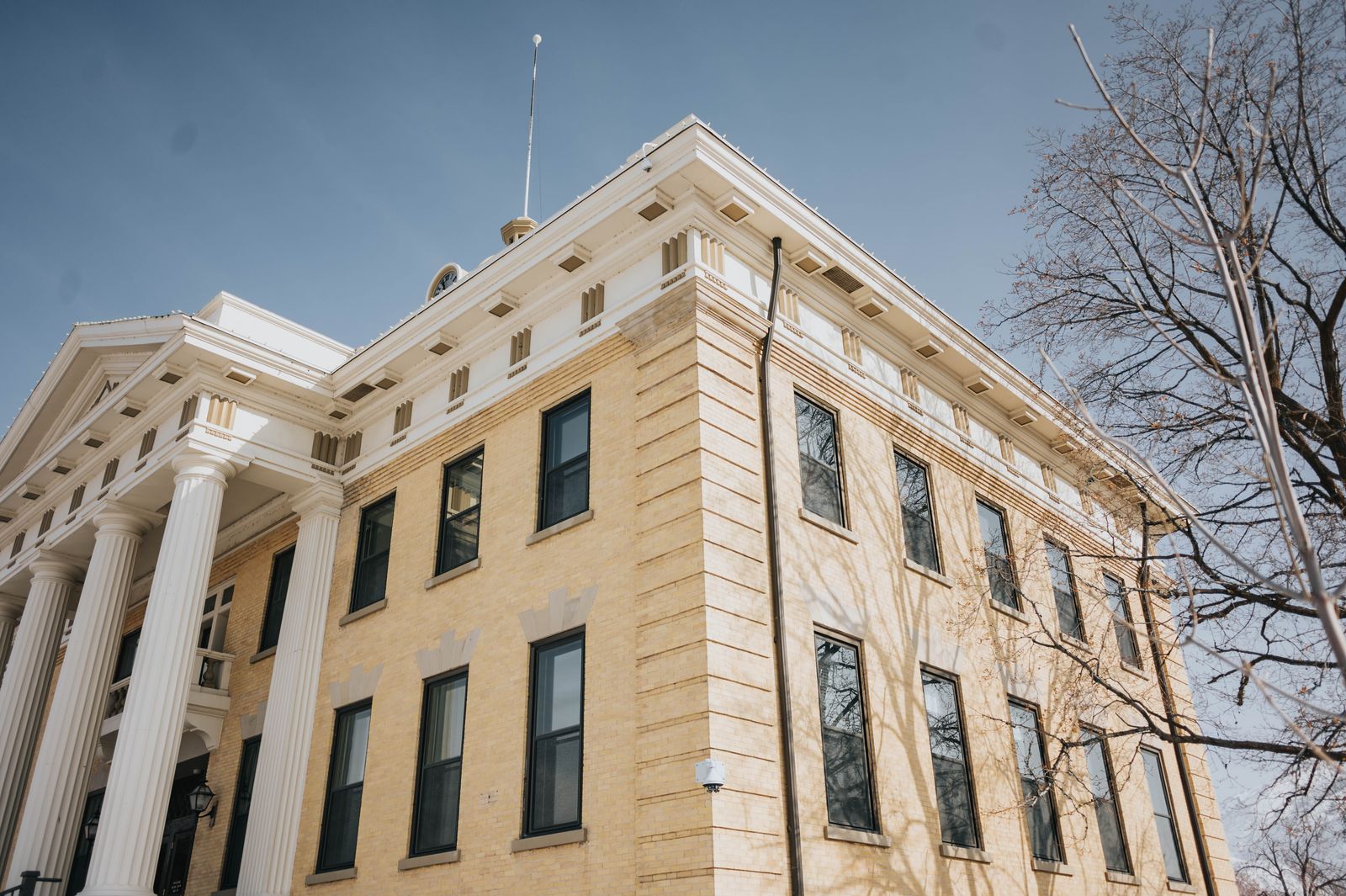 A historic county courthouse with white columns under a blue sky