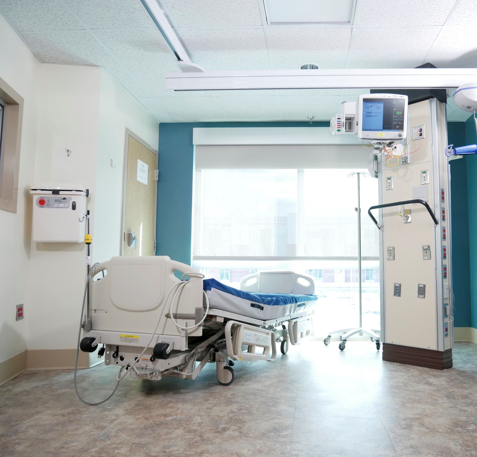 A single hospital room with a bed by a large window