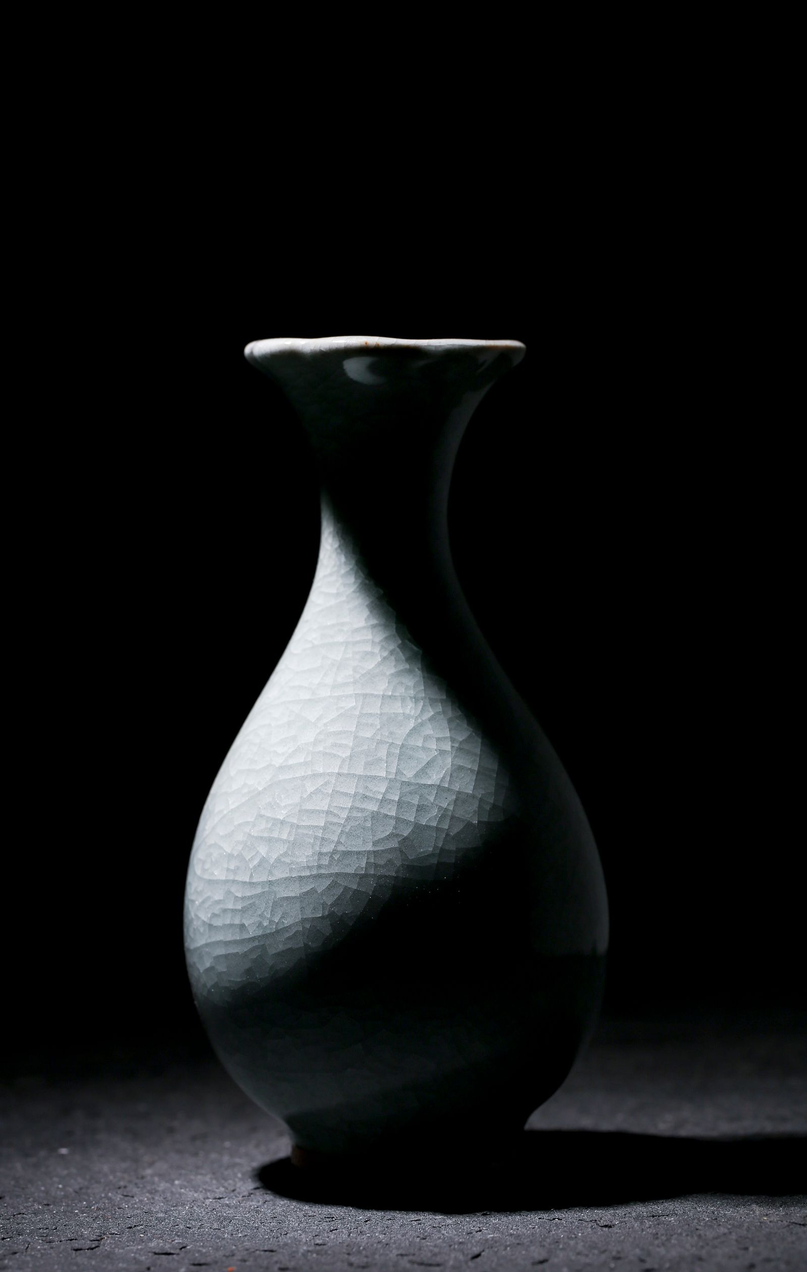 White crackle-glaze vase against a dark background