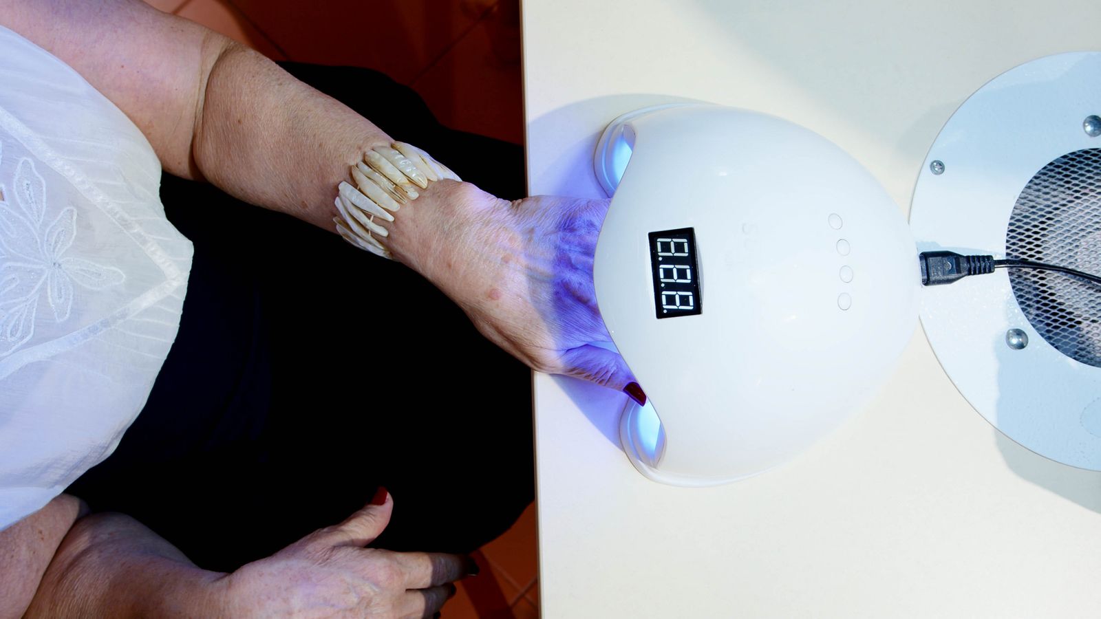 A hand resting in an LED lamp while the gel polish cures