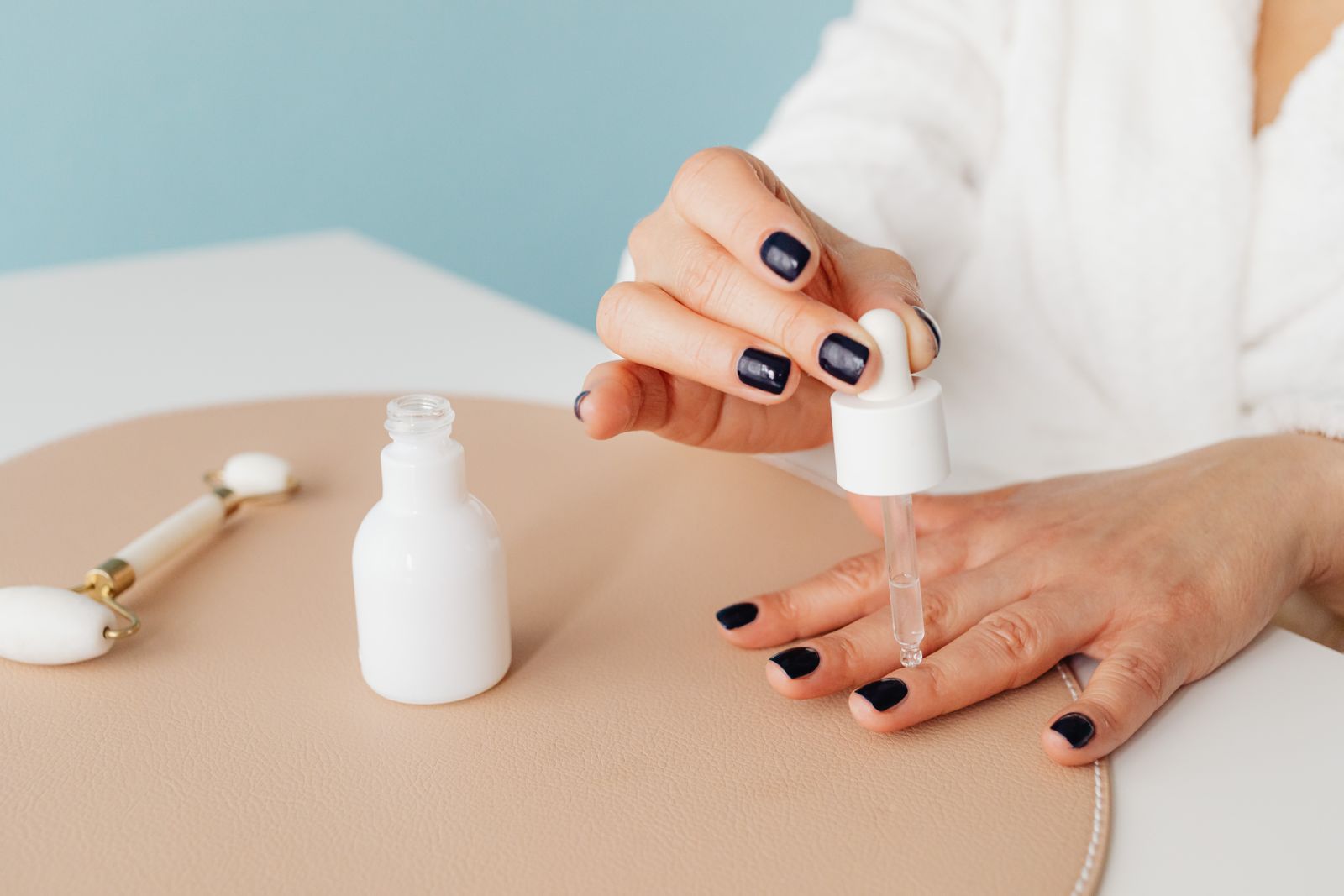 A drop of cuticle oil applied to dark painted nails