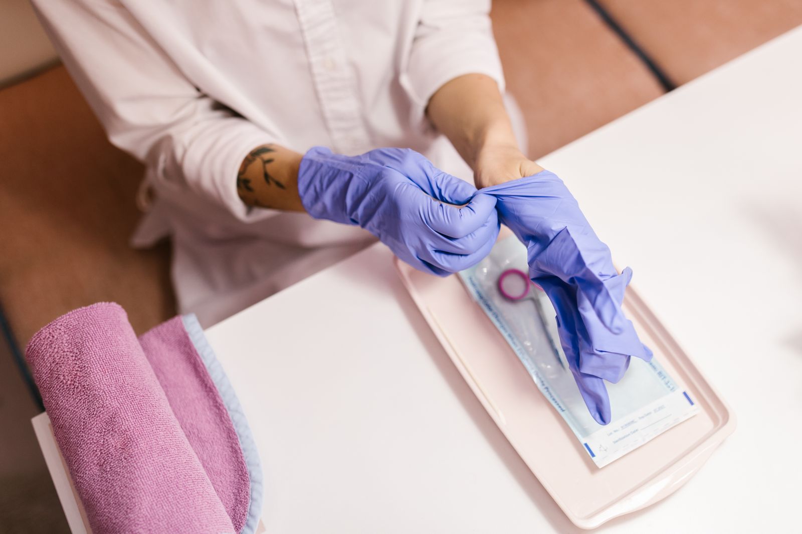 A technician in blue gloves opening a sealed pouch of sterilised tools