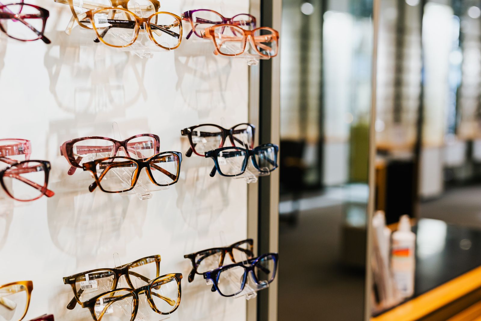 A wall of glasses frames in acetate colours on white shelves