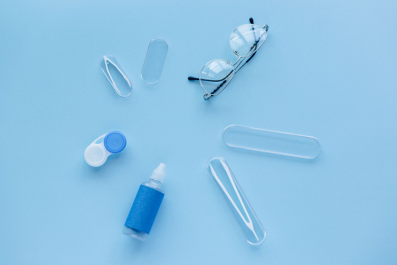 Contact lens case, solution and glasses on a blue background