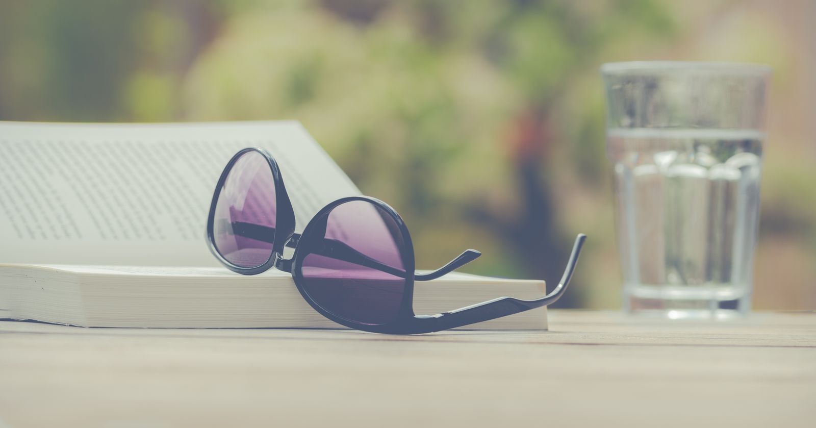 Sunglasses resting on an open book outdoors