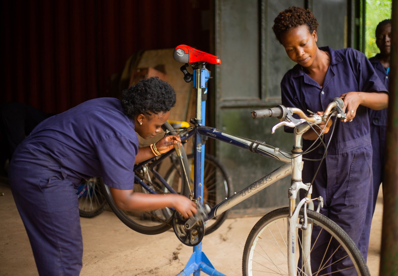 Two mechanics servicing a bicycle on a workstand