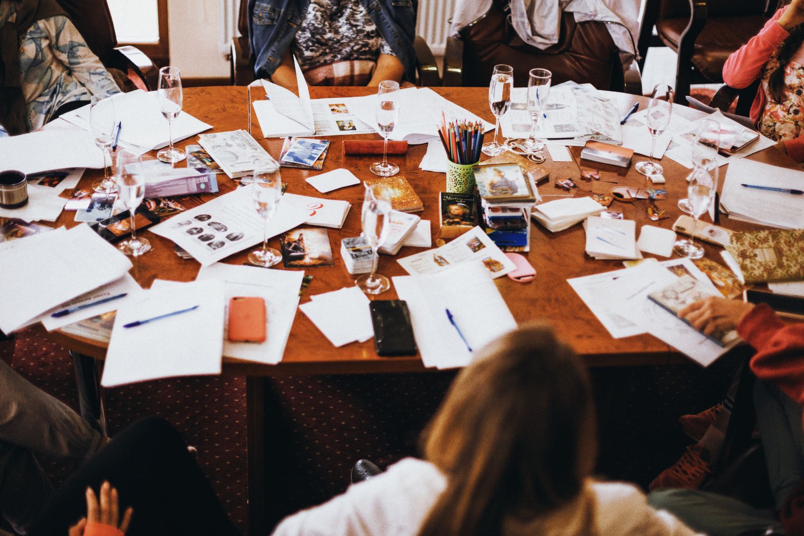 A table covered in printed pages, notes and pens seen from above