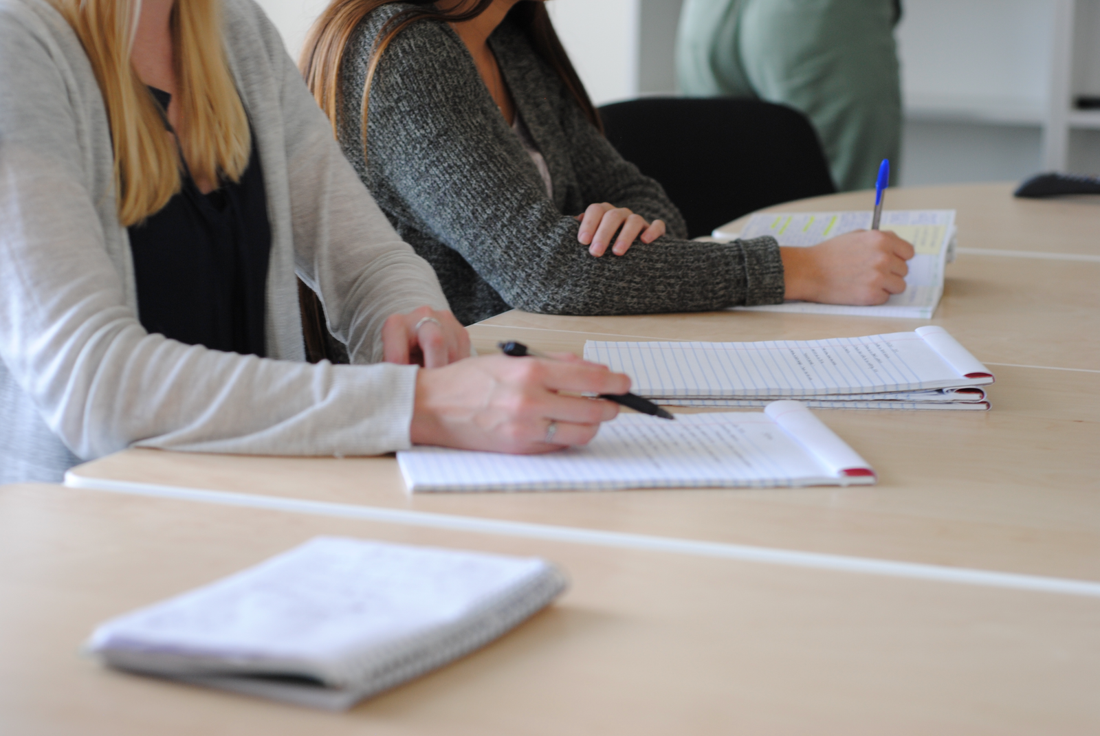 People writing in notebooks around a long table