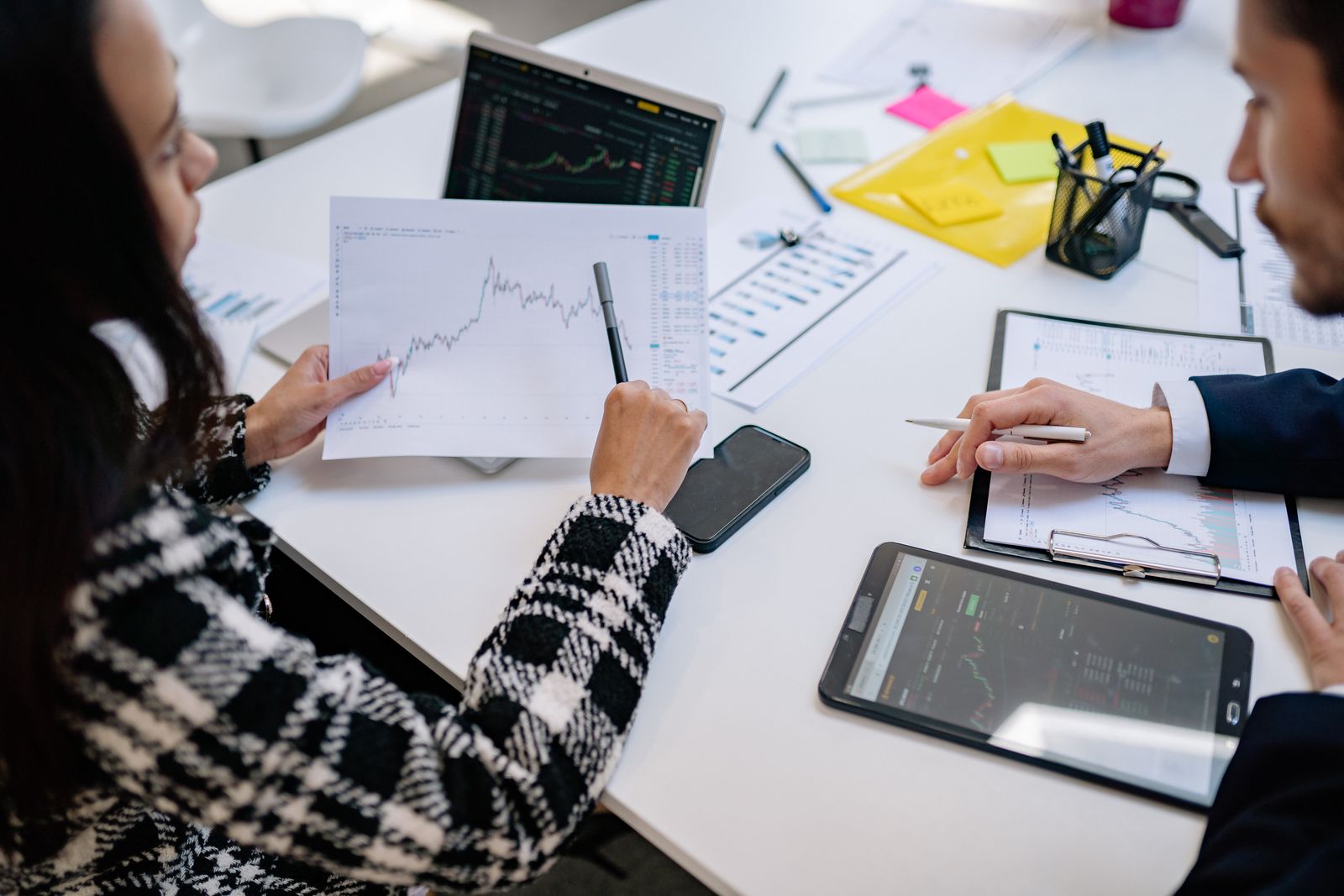 Colleagues reviewing printed charts and tablets together at a meeting table