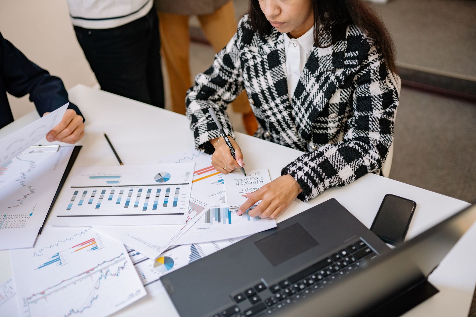 A woman reviewing printed charts beside a laptop at a meeting table