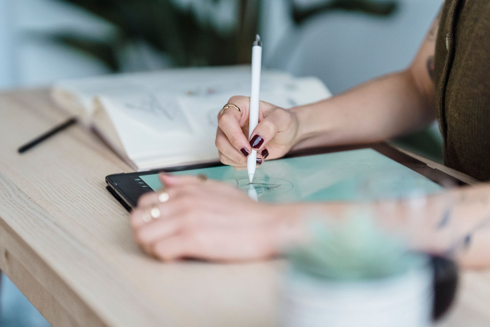 Hands drawing on a tablet with a stylus at a wooden desk