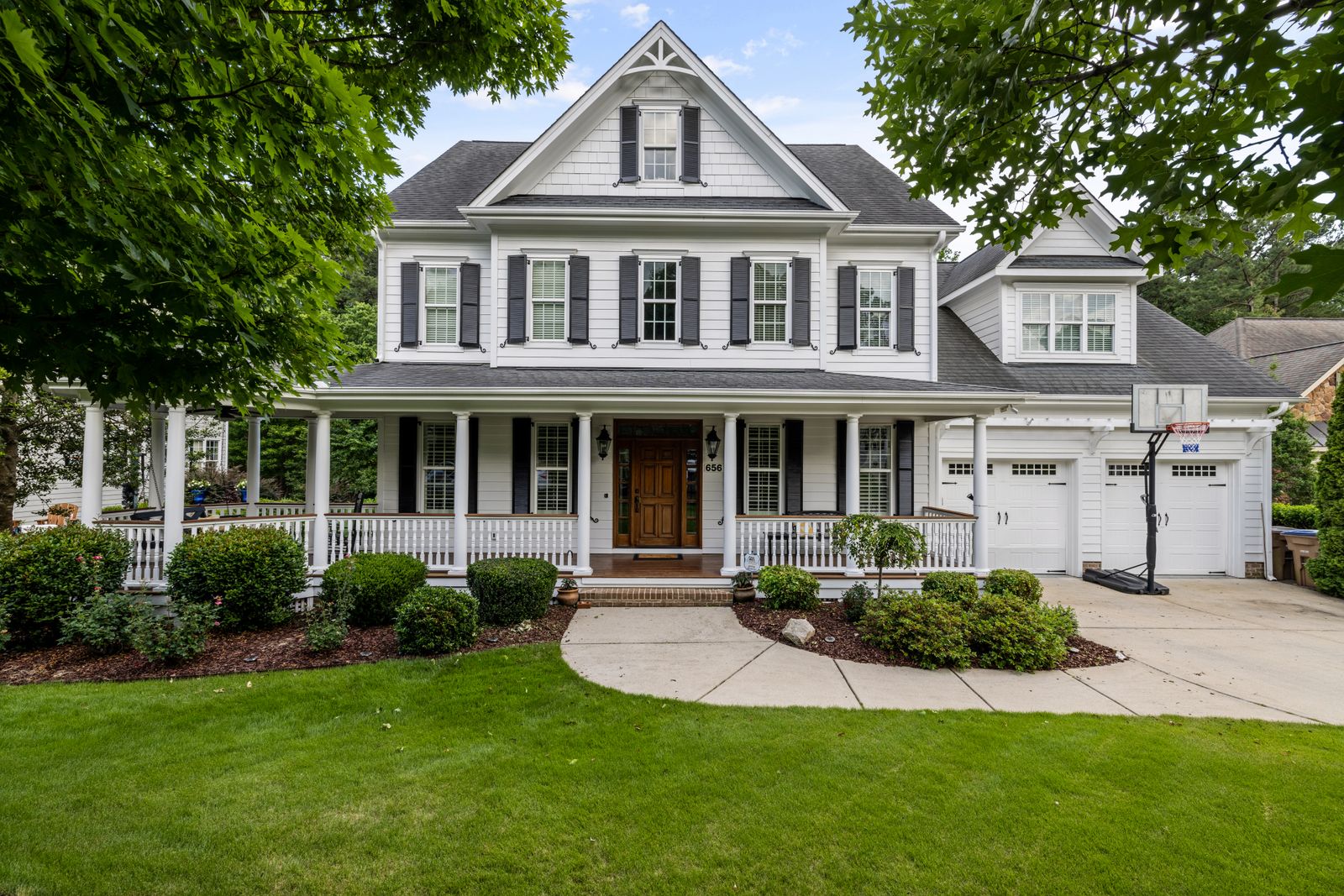 White two-storey house with a deep front porch, lawn and garage
