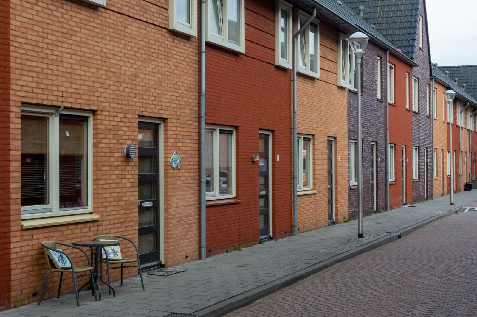 A street of brick row houses with large windows and small front terraces
