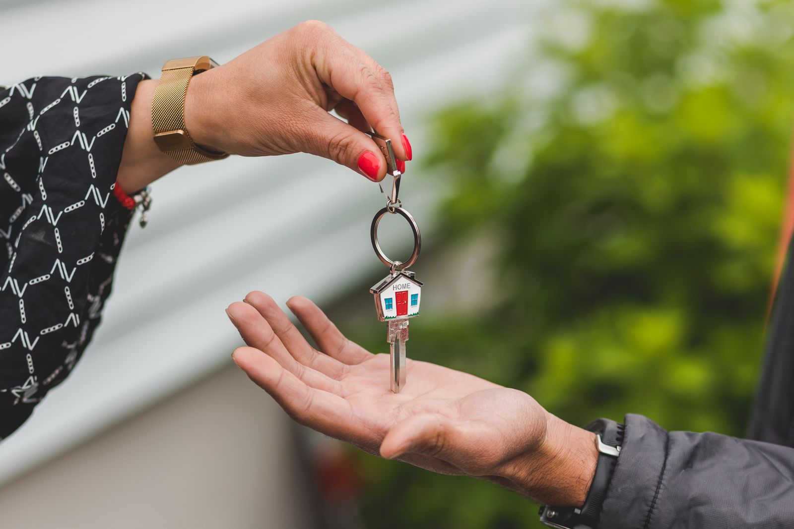 A hand passing a house key on a small house-shaped key ring