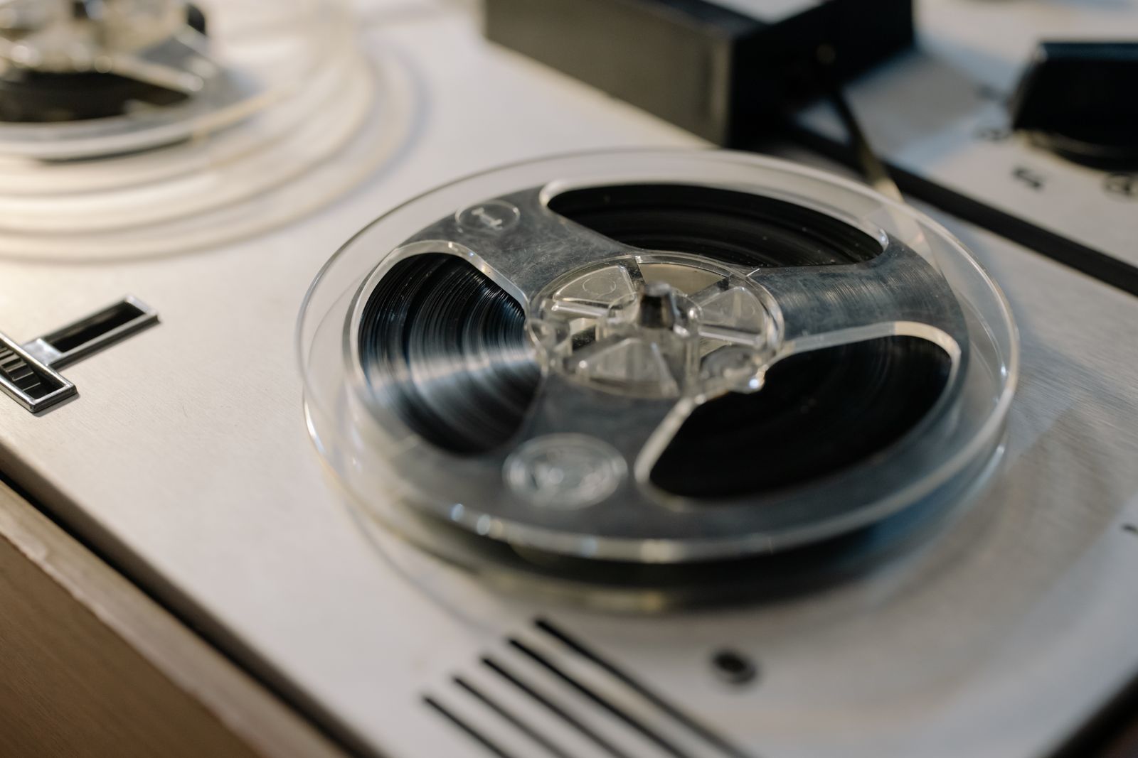 A clear tape reel wound with tape on a pale tape machine