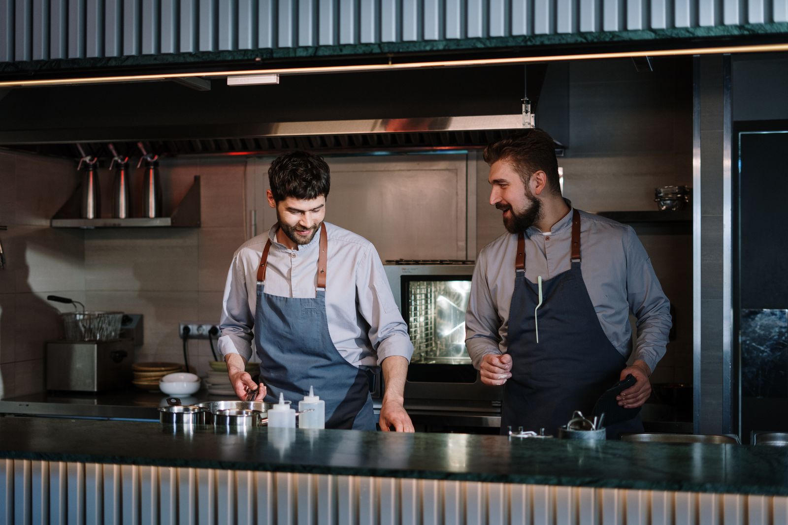 Two cooks in aprons preparing food in a restaurant kitchen