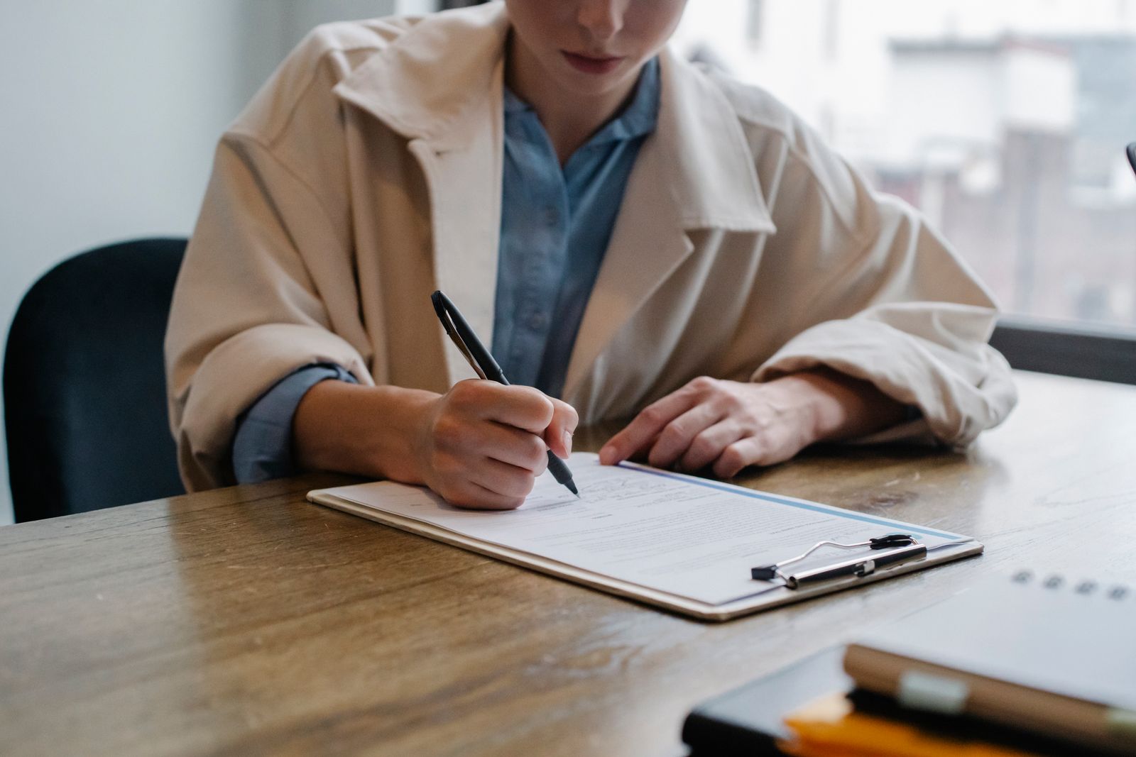 A job seeker filling in a form on a clipboard at a table