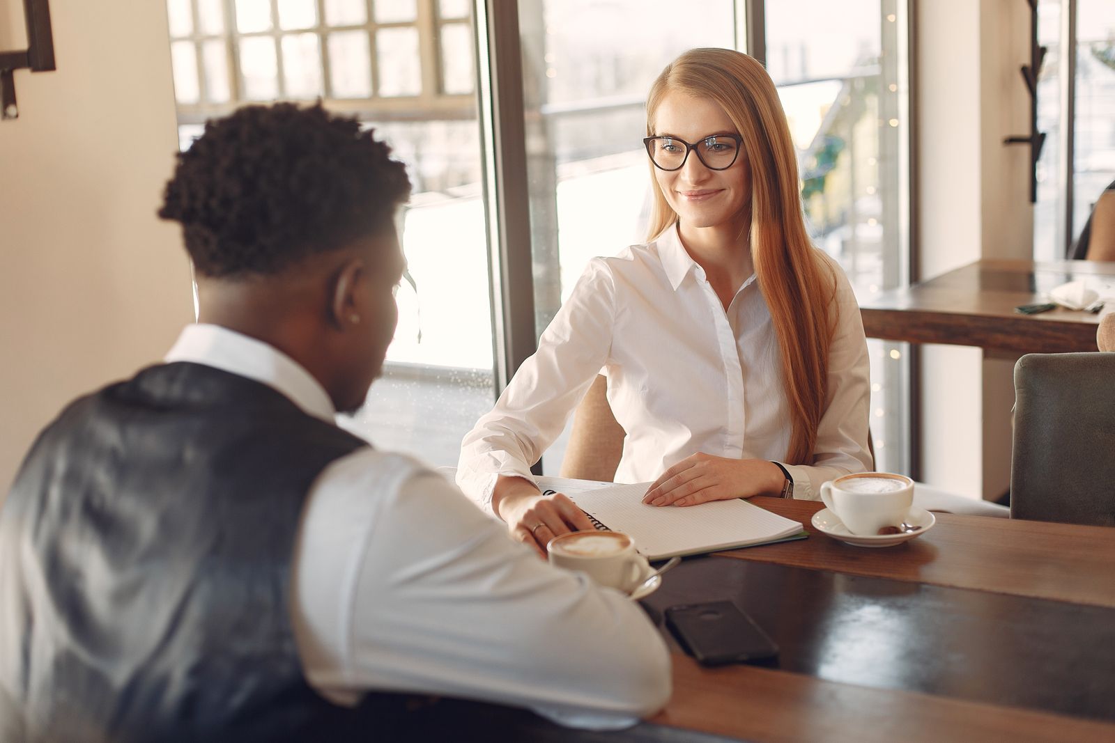A recruiter talking with a candidate across a desk with notes and a laptop